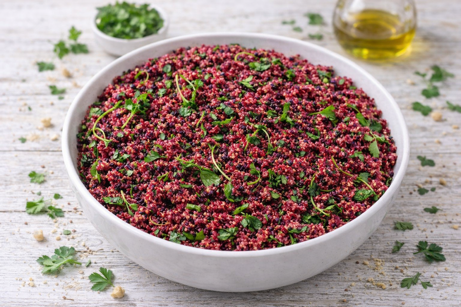 White bowl filled with red and green quinoa on a wooden surface