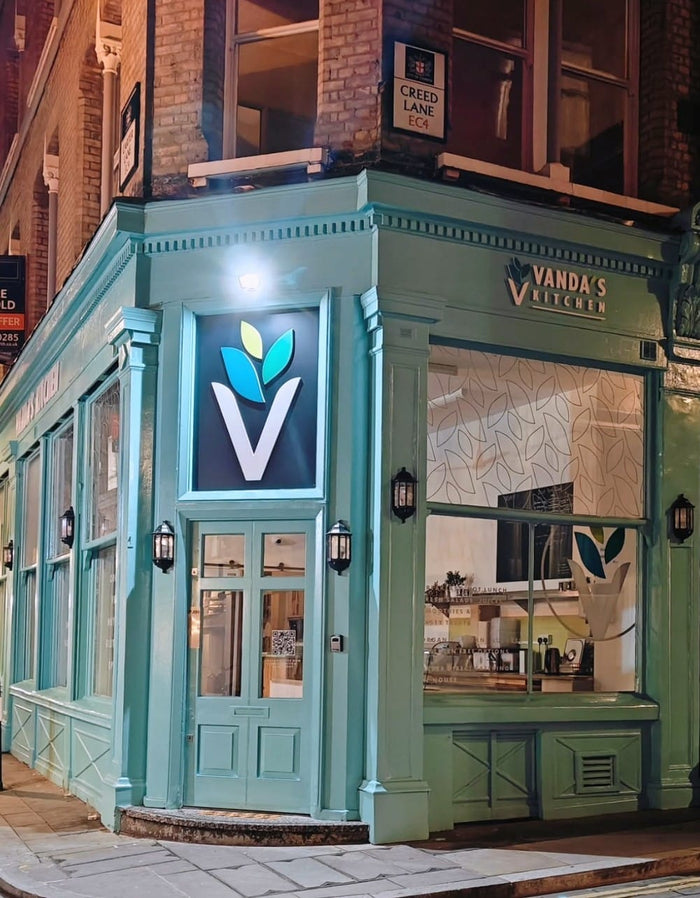Teal storefront with 'Vanda's' sign and logo at night